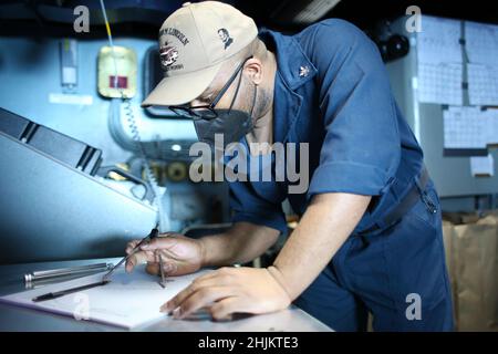 MER DES PHILIPPINES (janv23, 2022) Spécialiste des opérations 2nd classe Owen Pattersontaylor, de San Diego, trace la position des contacts de surface sur un panneau de manœuvre dans la salle des opérations tactiques à bord du porte-avions USS Abraham Lincoln (CVN 72) de la classe Nimitz.Faisant partie de la flotte du Pacifique des États-Unis, les unités affectées aux groupes de grève des transporteurs Carl Vinson et Abraham Lincoln, aux groupes prêts à l'amphibie d'Amérique et d'Essex, aux côtés de la Force d'autodéfense maritime du Japon, mènent une formation pour préserver et protéger une région Indo-Pacifique libre et ouverte. Banque D'Images