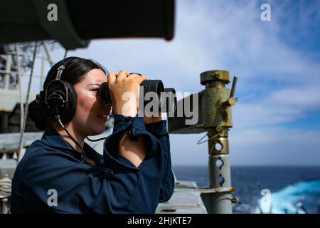 MER DES PHILIPPINES (janv23, 2022) le Matelot de 1re classe Cassandra Hortz, de Los Angeles, utilise des jumelles tout en étant sous surveillance à bord du porte-avions de la classe Nimitz USS Abraham Lincoln (CVN 72).Faisant partie de la flotte du Pacifique des États-Unis, les unités affectées aux groupes de grève des transporteurs Carl Vinson et Abraham Lincoln, aux groupes prêts à l'amphibie d'Amérique et d'Essex, aux côtés de la Force d'autodéfense maritime du Japon, mènent une formation pour préserver et protéger une région Indo-Pacifique libre et ouverte. Banque D'Images