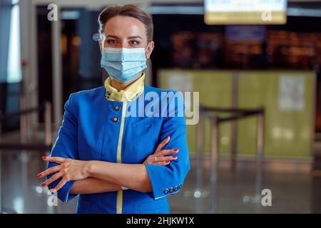 Un agent de bord dans un masque facial de protection situé dans le terminal de l'aéroport Banque D'Images
