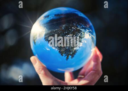 Regardez à travers une boule de cristal sur un paysage d'hiver, qui peut être vu à l'envers à travers le reflet. Banque D'Images