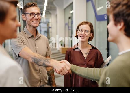 Portrait d'une équipe d'affaires moderne accueillant un nouvel employé se concentre sur un homme tatoué souriant se serrant la main avec le stagiaire Banque D'Images