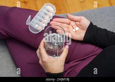 Une femme qui va prendre des comprimés de la boîte à pilules.Une femme prend des médicaments avec un verre d'eau.Concept de pharmacie et de soins de santé. Banque D'Images