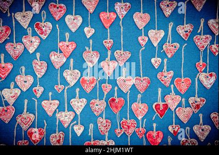 Coeurs rouges en céramique suspendus sur des cordes de chanvre sur fond bleu.Le cadre idéal pour la Saint-Valentin. Banque D'Images