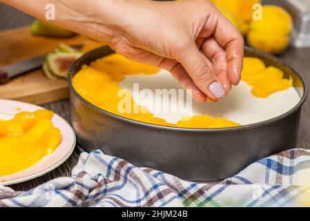 Cuisson du cheesecake.Le cuisinier décorera le cheesecake avec des tranches de fruits.Une femme décorera le cheesecake. Banque D'Images