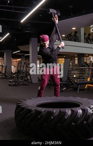 Un homme frappe une roue de sledgehammer en forme physique, le concept d'un style de vie sain masculin sledgehammer actif frapper sport, pour l'exercice de force pour adulte pour Banque D'Images