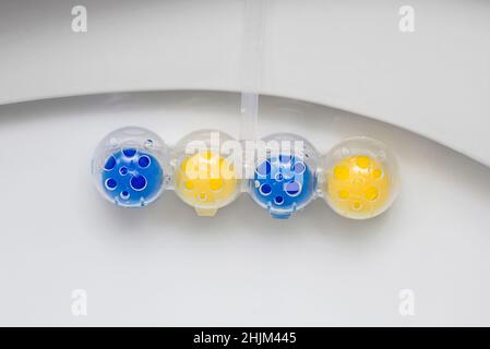 Nettoyez le bol des toilettes avec des boules nettoyantes et rafraîchissantes.Boules multicolores de nettoyant pour cuvette de toilette. Banque D'Images