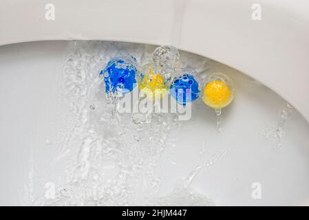 Nettoyez le bol des toilettes avec des boules nettoyantes et rafraîchissantes.Boules multicolores de nettoyant pour cuvette de toilette. Banque D'Images