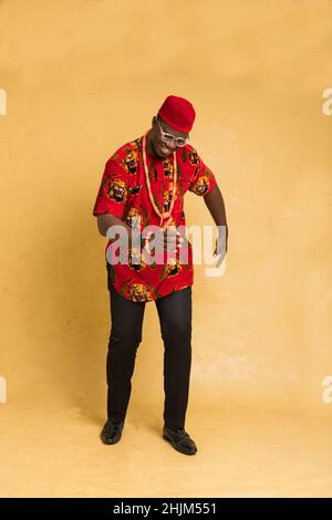 Igbo traditionnellement habillé homme d'affaires debout dansant Banque D'Images