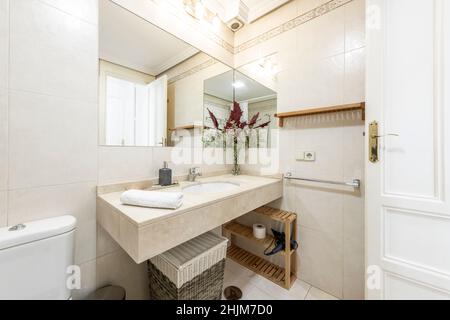 Salle de bains avec dessus en marbre crème, évier en porcelaine et miroir intégré dans l'appartement de location Banque D'Images