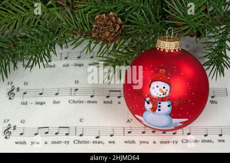 Ornement de Noël rouge avec bonhomme de neige sur la musique de vacances avec brogh de pin vert Banque D'Images