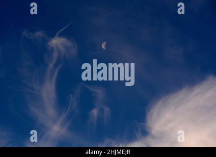 Une lune du dernier quart, parfois appelée demi-lune, partage le ciel avec des nuages cirrus plus sages au-dessus de Santa Fe, Nouveau-Mexique. Banque D'Images