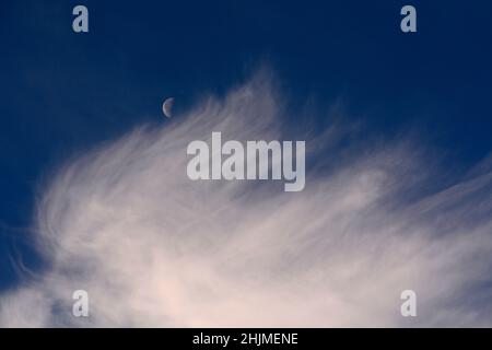 Une lune du dernier quart, parfois appelée demi-lune, partage le ciel avec des nuages cirrus plus sages au-dessus de Santa Fe, Nouveau-Mexique. Banque D'Images