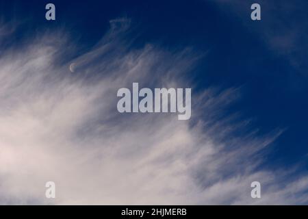 Une lune du dernier quart, parfois appelée demi-lune, partage le ciel avec des nuages cirrus plus sages au-dessus de Santa Fe, Nouveau-Mexique. Banque D'Images