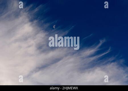 Une lune du dernier quart, parfois appelée demi-lune, partage le ciel avec des nuages cirrus plus sages au-dessus de Santa Fe, Nouveau-Mexique. Banque D'Images