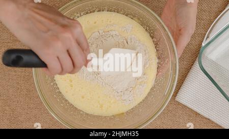 Recette de gâteau aux pommes avec base de biscuit, processus de cuisson étape par étape.Mélanger les œufs, le sucre et la farine dans un bol en verre, poncer à plat.Gros plan des ingrédients sur le kit Banque D'Images