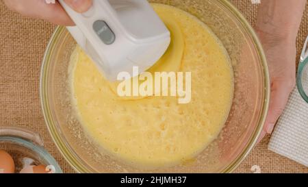 Recette de gâteau aux pommes avec base de biscuit, processus de cuisson étape par étape.Mélanger les œufs et le sucre dans un bol en verre, poncer à plat.Gros plan des ingrédients sur la languette de la cuisine Banque D'Images