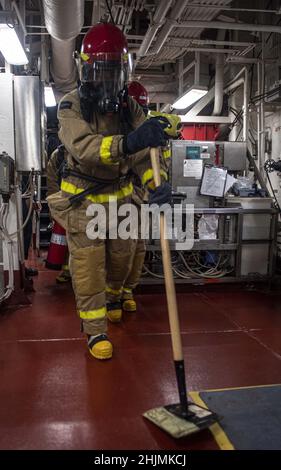 MER DES PHILIPPINES (janv29, 2022) le pompier Brandon Arreola, de San Diego, affecté au navire d'assaut amphibie déployé à l'avant USS America (LHA 6), simule la mise en place de braises à chaud dans la salle des machines principales du navire lors d'un exercice de lutte contre les incendies dans l'espace de machines.L'Amérique, navire chef de file du America Amphiobie Ready Group, ainsi que l'unité expéditionnaire maritime 31st, opère dans la zone de responsabilité de la flotte américaine 7th afin d'améliorer l'interopérabilité avec les alliés et les partenaires et de servir de force de réaction prête à l'emploi pour défendre la paix et la stabilité dans la région Indo-Pacifique.(É.-U.Bleu marine photo par masse commun Banque D'Images