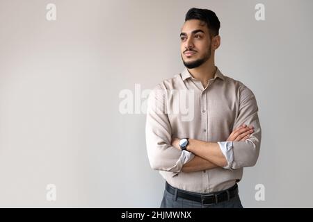 Studio portrait d'un homme indien sérieux regardant de côté debout sur un copyspace gris Banque D'Images