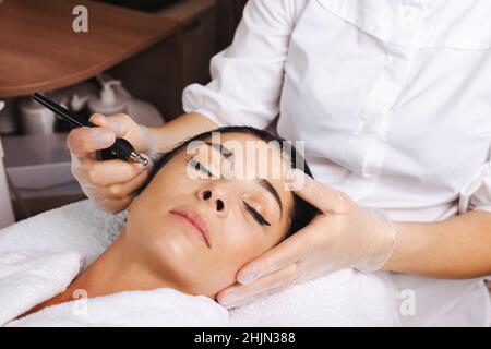 Portrait rapproché d'une femme visage recevant un traitement de micro-courant facial à l'aide d'appareils d'impulsions électriques dans un salon de spa.Soins de santé.Beauté de la peau Banque D'Images