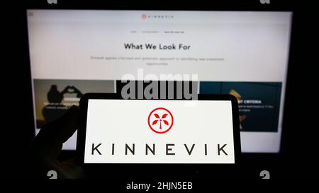 Personne tenant un smartphone avec le logo de la société suédoise d'investissement Kinnevik AB sur l'écran devant le site Web.Mise au point sur l'affichage du téléphone. Banque D'Images