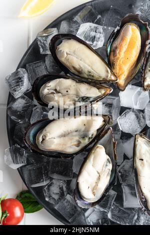 attention sélective. moules crues dans l'évier, étalées sur glace sur une assiette. une spécialité chère. service de restaurant Banque D'Images