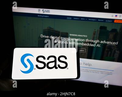 Personne tenant un téléphone portable avec le logo de la société américaine de logiciels d'analyse SAS Institute Inc. À l'écran devant la page Web.Mise au point sur l'affichage du téléphone. Banque D'Images