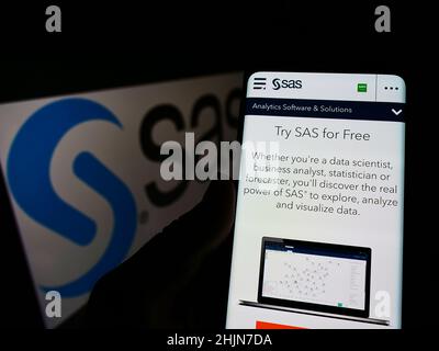 Personne tenant un téléphone portable avec le site Web de la société américaine de logiciels d'analyse SAS Institute Inc. À l'écran avec logo.Concentrez-vous sur le centre de l'écran du téléphone. Banque D'Images
