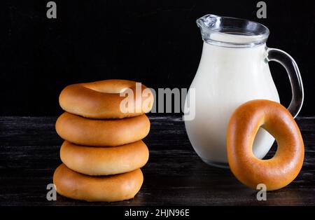 Pot à lait en pile et de bagels sur fond noir Banque D'Images