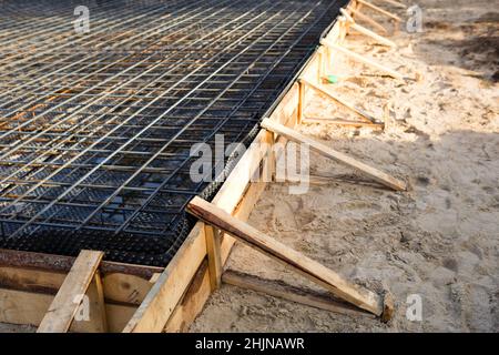 Les ferrures sur une coffrage en bois avec des tuyaux coudés sont la base pour verser la fondation de la maison avec une dalle de béton. Construction de chalet Banque D'Images