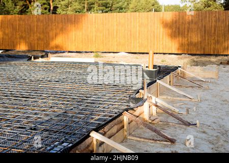 Les ferrures sur une coffrage en bois avec des tuyaux coudés sont la base pour verser la fondation de la maison avec une dalle de béton. Construction de chalet Banque D'Images