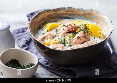 Soupe de poisson norvégien à la truite, aux pommes de terre et au maïs, fond gris.Soupe de saumon et de pommes de terre. Banque D'Images