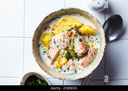 Soupe de poisson norvégienne avec truite, pommes de terre et maïs, fond de carreaux blancs.Soupe de saumon et de pommes de terre. Banque D'Images