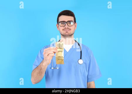 Médecin stagiaire portant des préservatifs sur fond bleu Banque D'Images