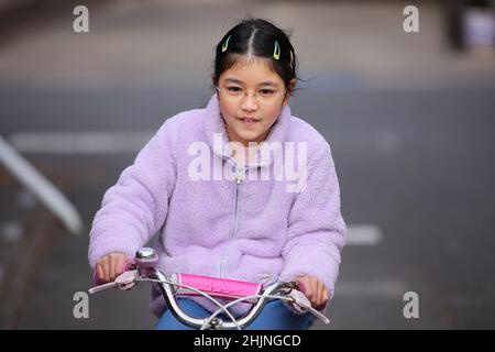 Naviguez dans le week-end sur son vélo rose préféré, portant une polaire violette confortable. Meilleur jour de tous les temps ! Banque D'Images