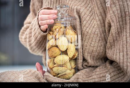 Pot en verre avec biscuits noix et lait condensé dans les mains des femmes. Banque D'Images