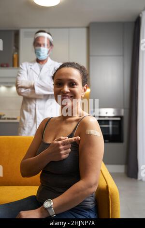 Une femme joyeuse qui pointe sur le bandage adhésif de son épaule Banque D'Images