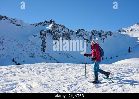 Belle femme senior raquette dans la neige l belle femme senior raquette dans le paysage de montagne enneigé de Kleinwalsertal dans le Vorarlberg, Autriche Banque D'Images