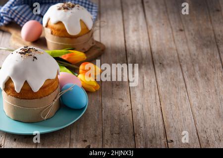 Gâteau traditionnel de Pâques, œufs colorés et tulipes sur une table en bois. Banque D'Images