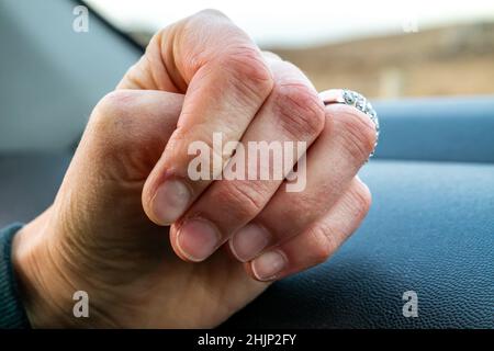 Les mains des femmes avec les doigts rouges gelés dans la voiture. Banque D'Images