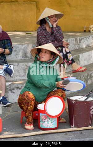 Une femme vietnamienne vendeur de nourriture de rue portant un chapeau conique traditionnel vend des aliments cuits dans les rues de Hoi an, province de Quang Nam, centre du Vietnam Banque D'Images