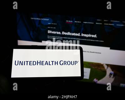 Personne tenant un téléphone portable avec le logo de la société américaine de soins de santé UnitedHealth Group Inc. À l'écran en face de la page Web.Mise au point sur l'affichage du téléphone. Banque D'Images