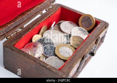 une petite vieille poitrine en bois avec des pièces sur fond blanc. épargne et inflation Banque D'Images