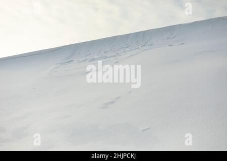 Pente enneigée contre le ciel.Avalanche de neige sur la crête de montagne.Temps d'hiver.Blanc désert dans le froid. Banque D'Images