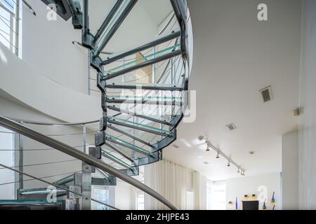 Intérieur moderne d'une maison privée de luxe.Gros plan de l'escalier en colimaçon en verre et en métal.Murs blancs. Banque D'Images