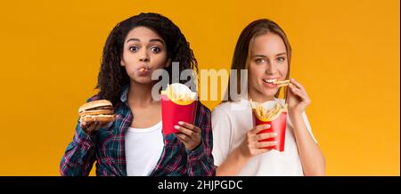 Happy Women tenant des frites hamburger Eating au studio Banque D'Images