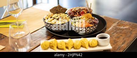 Banderole ou affiche supérieure horizontale avec bol de poisson à pois ou de poisson cru mariné et raviolis à la vapeur sur une table dans un restaurant fusion moderne - Orient Banque D'Images