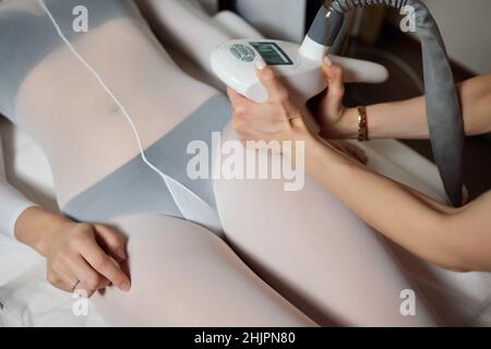 Femme en costume blanc couchant un tomach de son, obtenant un massage GPL dans un spa Banque D'Images