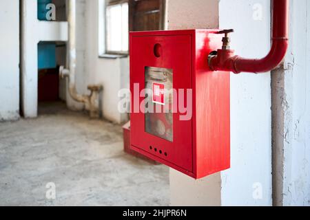 Tuyau d'incendie dans une boîte rouge.Rouleau de tuyaux pour l'urgence incendie dans armoire en métal rouge sur mur blanchi gris blanchi à la chaux dans le cadre du système de lutte contre l'incendie de l'industrie Banque D'Images