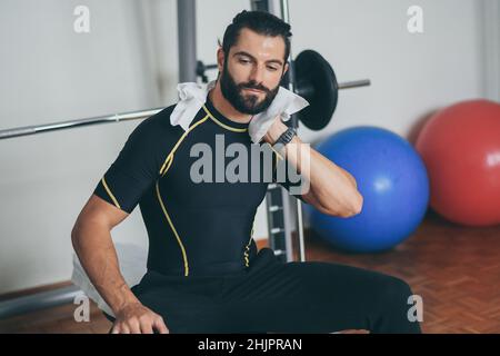 Beau homme essuye la sueur après une séance d'entraînement.Jeune garçon sportif à la fin de l'entraînement dans la salle de gym.Athlète en sueur avec une serviette à la main prête à Banque D'Images