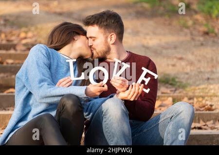 Jeune couple jouant avec des lettres blanches d'amour Banque D'Images
